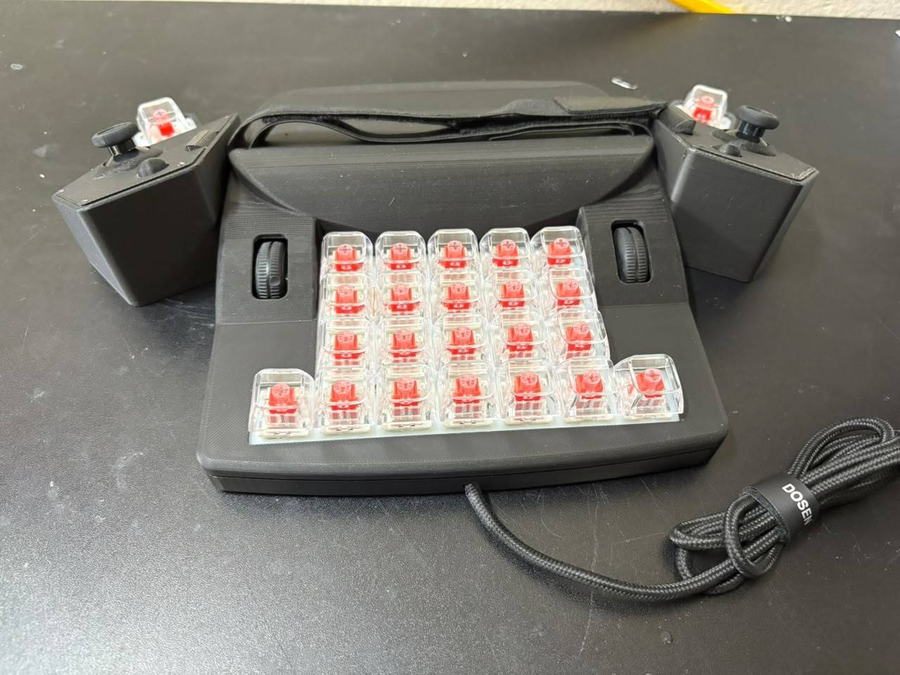 Front view of the ERCHAM MK1 functional prototype with thumb clusters mounted on both sides, two scroll wheels, and a braided USB cable